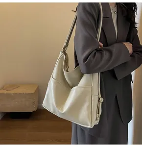Close-up of beige leather tote bag featuring double front pockets and adjustable metal buckle