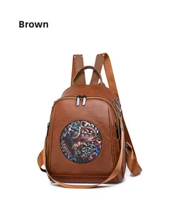 Detail of vintage brown PU leather backpack featuring a colorful elephant pattern embroidery