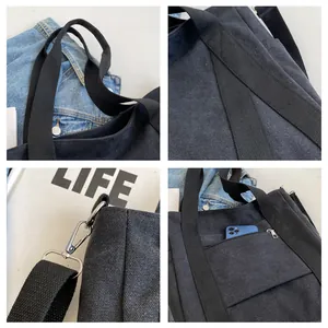 Detail of black canvas tote showing silver hardware, zipper pocket, and durable texture