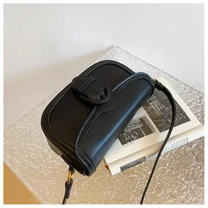 Détail d'un sac bandoulière vintage en cuir noir mat avec rabat semi-circulaire et boucle