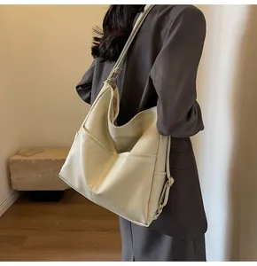 Detail view of cream leather tote bag showing side pocket and long shoulder strap texture