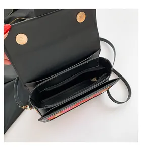 Detail view of the black floral crossbody bag interior with zipper pocket and magnetic snaps