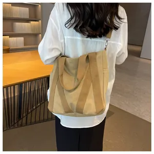 Detail of khaki canvas tote bag showing wide shoulder straps and side pocket design
