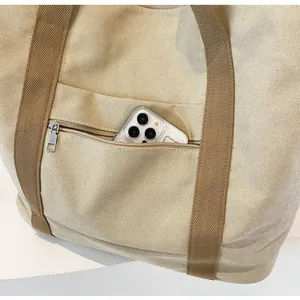 Detailaufnahme der Vordertasche einer Canvas-Tasche mit Metall-Reißverschluss und Handyfach
