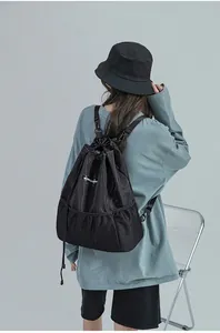 Détail du sac à dos noir à cordon avec poche en maille sur modèle féminin de dos