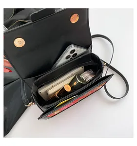 Close-up of black crossbody bag interior with dual gold magnetic clasps and floral print