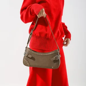 Sac à bandoulière vintage marron avec clous sur fond de maille rouge