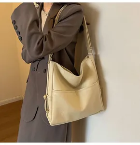 Detail view of cream oversized tote bag with dual front pockets and adjustable strap
