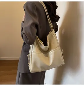 Detail of soft cream faux leather tote bag with lychee texture and open front pocket