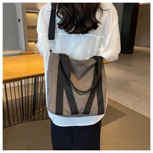 Detail of a large brown canvas tote bag with black straps and adjustable shoulder strap