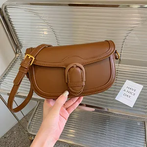Sac à bandoulière compact en cuir marron caramel avec une grande boucle décorative