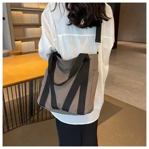 Detail of canvas tote bag showing side pocket, thick nylon strap and textured fabric