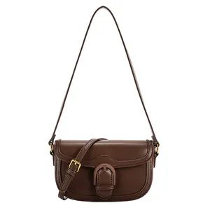 Sacoche rétro en cuir marron foncé avec boucle dorée sur un fond blanc neutre