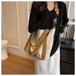 Detail of canvas tote bag showing khaki webbing straps and side pocket in home setting