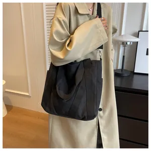 Close-up of black canvas tote bag with adjustable shoulder strap and side pocket