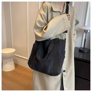Detail of a large black canvas tote bag with adjustable shoulder strap and side pocket