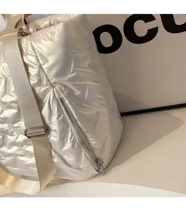 Detail of pearl white quilted shoulder bag with V-shaped stitching and adjustable strap