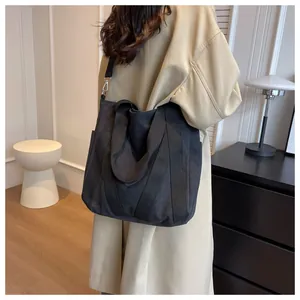 Close-up of a large black canvas tote bag with adjustable straps in a minimalist room
