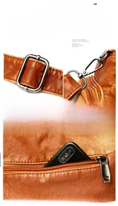 Close-up of brown washed leather texture, metal buckles, and back zipper pocket for phone