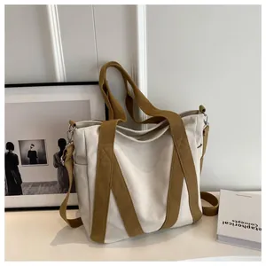Detail showing high-quality beige canvas tote bag with brown straps and side pockets