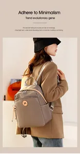 Detail view of khaki Oxford cloth backpack featuring a minimalist circular M logo and zipper