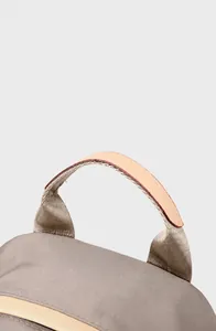 Detalle del asa de cuero ergonómica en una mochila de nailon gris claro con costuras