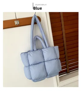 Detail view of a quilted light blue puffer tote bag with square padding hanging on a hook