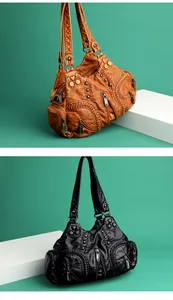 Detail of vintage washed leather tote with heart buckle and multiple zipper pockets