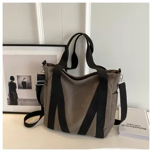 Detail of a large canvas tote bag with black strap and metallic silver buckles