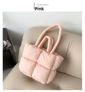 Detail of pink padded tote bag with quilted square texture on a beige leather sofa
