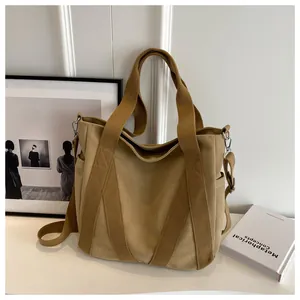 Detail of khaki canvas tote bag showing side pocket, metal hardware and shoulder strap