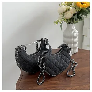 Detalle de bolsos media luna de mezclilla acolchada negra con cadena metálica y dije