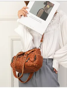 Detailed macro of a vintage brown leather crossbody bag with braided trim and zippers