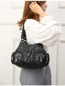 Detail of vintage black washed faux leather shoulder bag with zipper and rivets