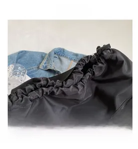 Detail of black nylon drawstring tote bag with elegant pleats and side pocket hardware