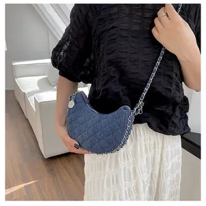 Primer plano del bolso media luna de mezclilla azul acolchado con cadena en el modelo