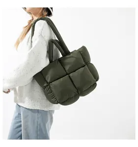 Close-up of deep green quilted puffer tote bag with puffy square pattern and soft handles