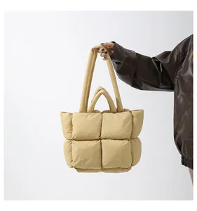 Detail of a beige quilted puffer tote bag featuring a padded texture and dual-strap design