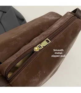 Close-up of vintage brown leather bag featuring a smooth gold-tone metal zipper pull