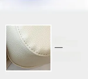 Détail du sac seau crème montrant le cuir grainé litchi et les coutures de précision