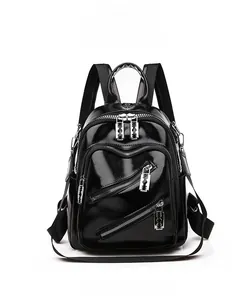 Détail frontal du sac à dos en similicuir noir brillant avec zips argentés en lame