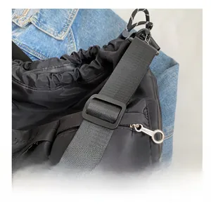 Detail view of the black nylon shoulder bag showing adjustable buckle and wide strap texture