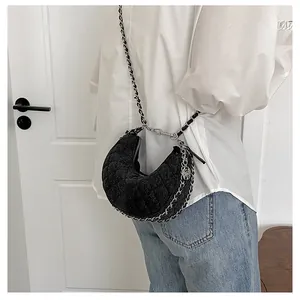 Detalle del bolso media luna acolchado negro con cadena de plata y dije de rosa