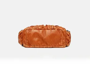 Detail view of the flat bottom and woven texture on a vintage brown leather handbag
