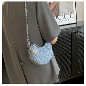 Detalle del bolso media luna de mezclilla azul con acolchado y colgante de rosa de plata