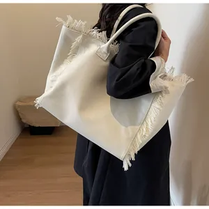 Vue détaillée du sac cabas en toile crème avec franges bohèmes et grande capacité de rangement