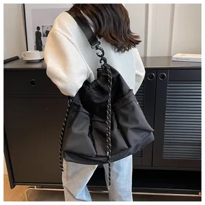 Detail of large black nylon crossbody bag with multi-pocket design and drawstring closure