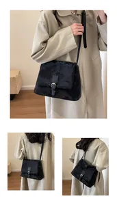 Detail of vintage black crossbody bag with flap cover and silver buckle on tan trench coat