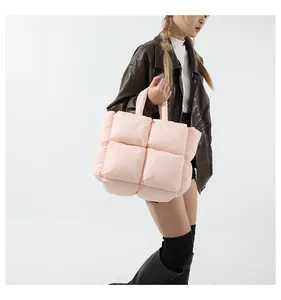 Close-up of a light pink quilted puffer tote bag carried by a model in a leather jacket