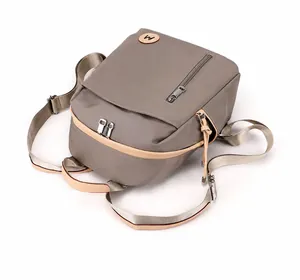 Detalle de mochila de nailon impermeable color topo con ribete de cuero y cremalleras de plata